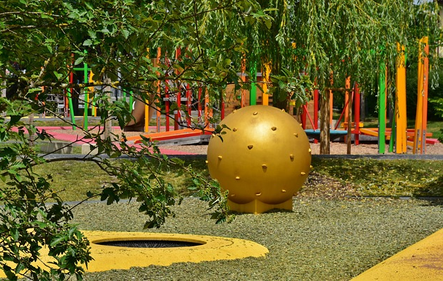 Bild 1: Verschiedene Spielplatzbereiche - Hüpfbereich vorn, Kugel mit Noppen in der Bildmitte und Klettergerüst im Hintergrund